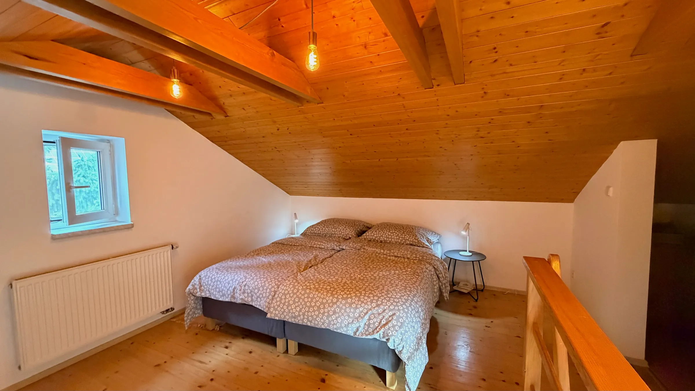 Podkrovní ložnice s oknem pod dřevěným stropem